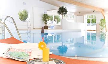 Drink und Zeitschrift neben dem Pool