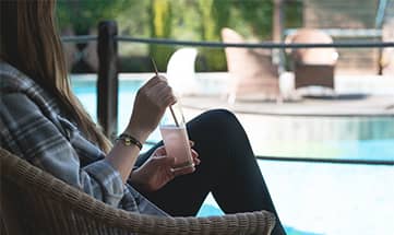 Frau genießt einen Drink am Pool