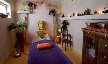 Stimmungsvoller Anwendungsraum mit Massageliege und zahlreichen Kerzen