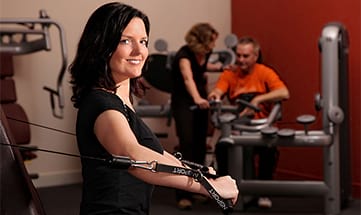 Frau in Fitnessraum trainiert an einem Gerät